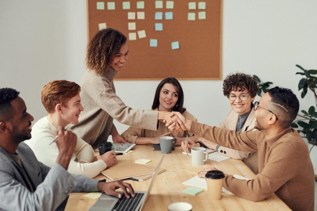 Équipe diversifiée collaborant lors d'une réunion, illustrant le travail d'équipe et la coopération sur un lieu de travail moderne.